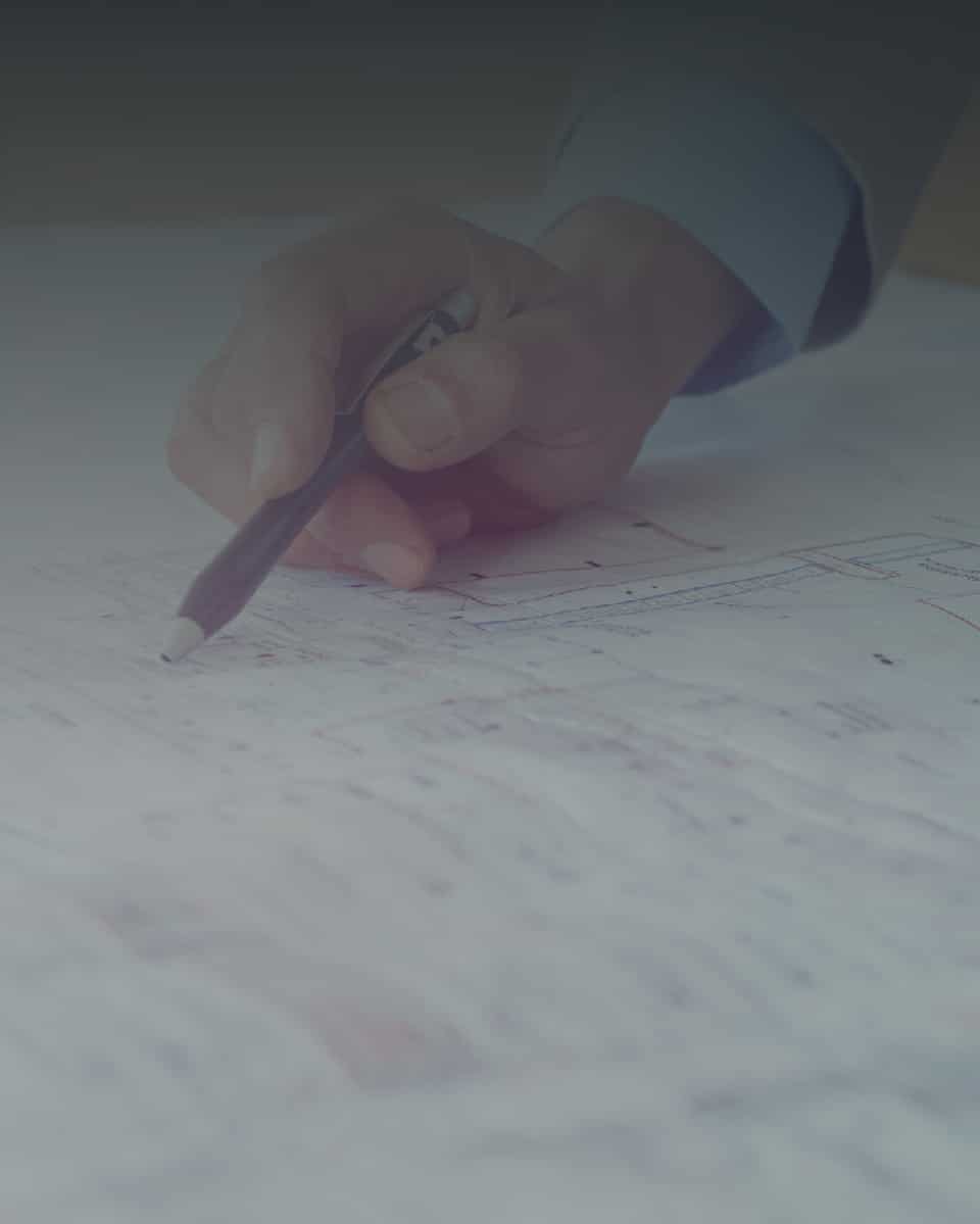 A hand pointing with a pen at a blueprint
